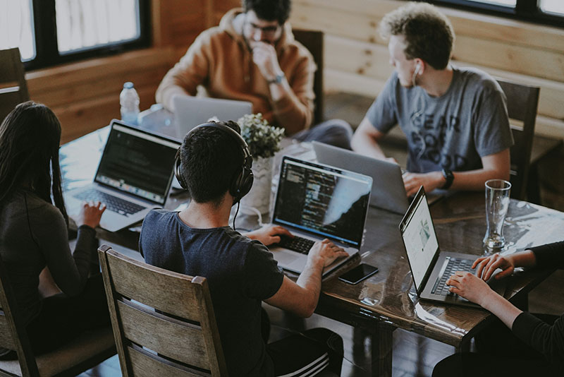 A group of young professionals work at a community desk.