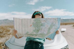 A young driver examines a road map, symbolizing how location and other unexpected factors can impact your car insurance premium.