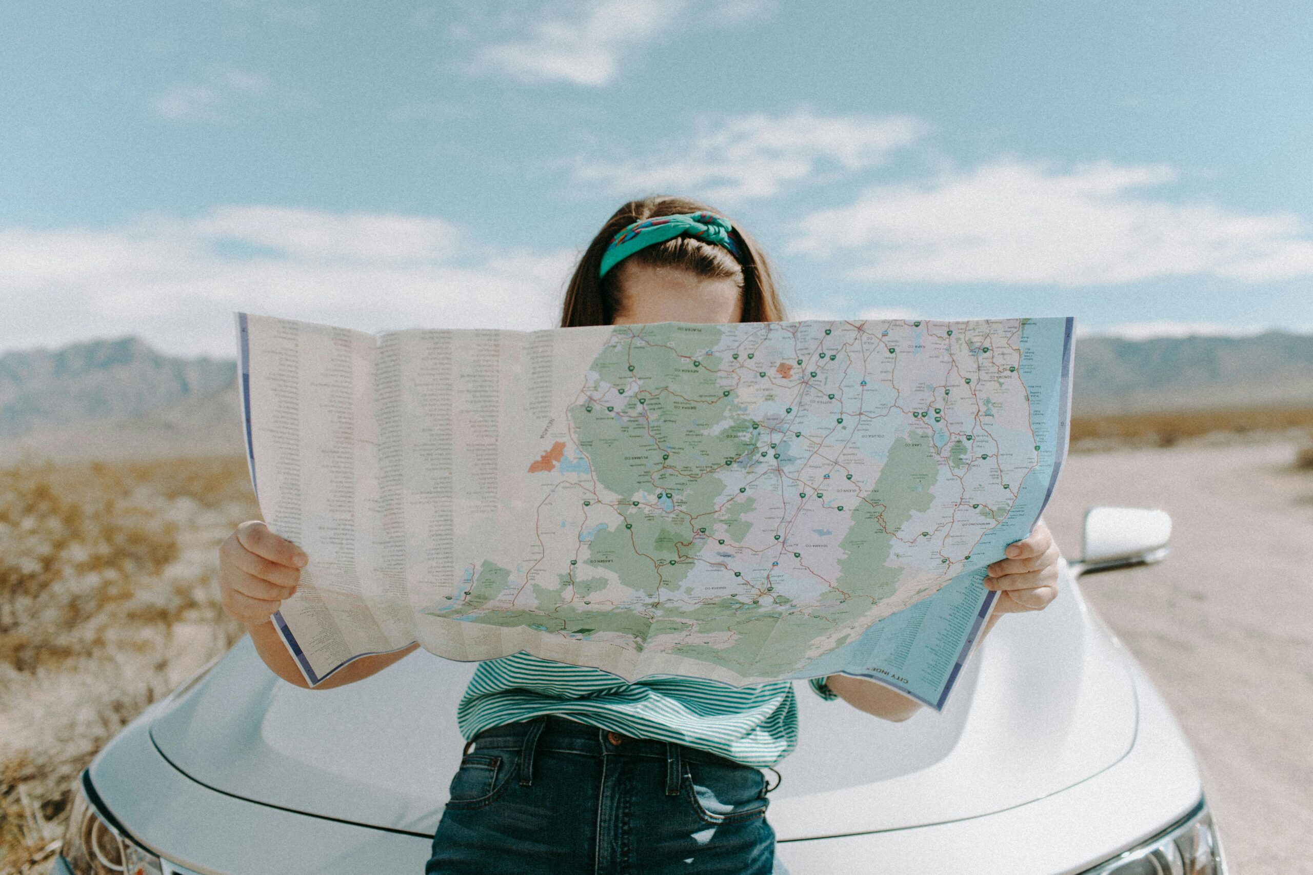 A young driver examines a road map, symbolizing how location and other unexpected factors can impact your car insurance premium.