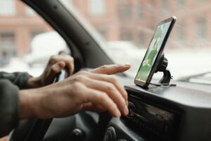 Man's hand pointed at a mounted phone on his dashboard.